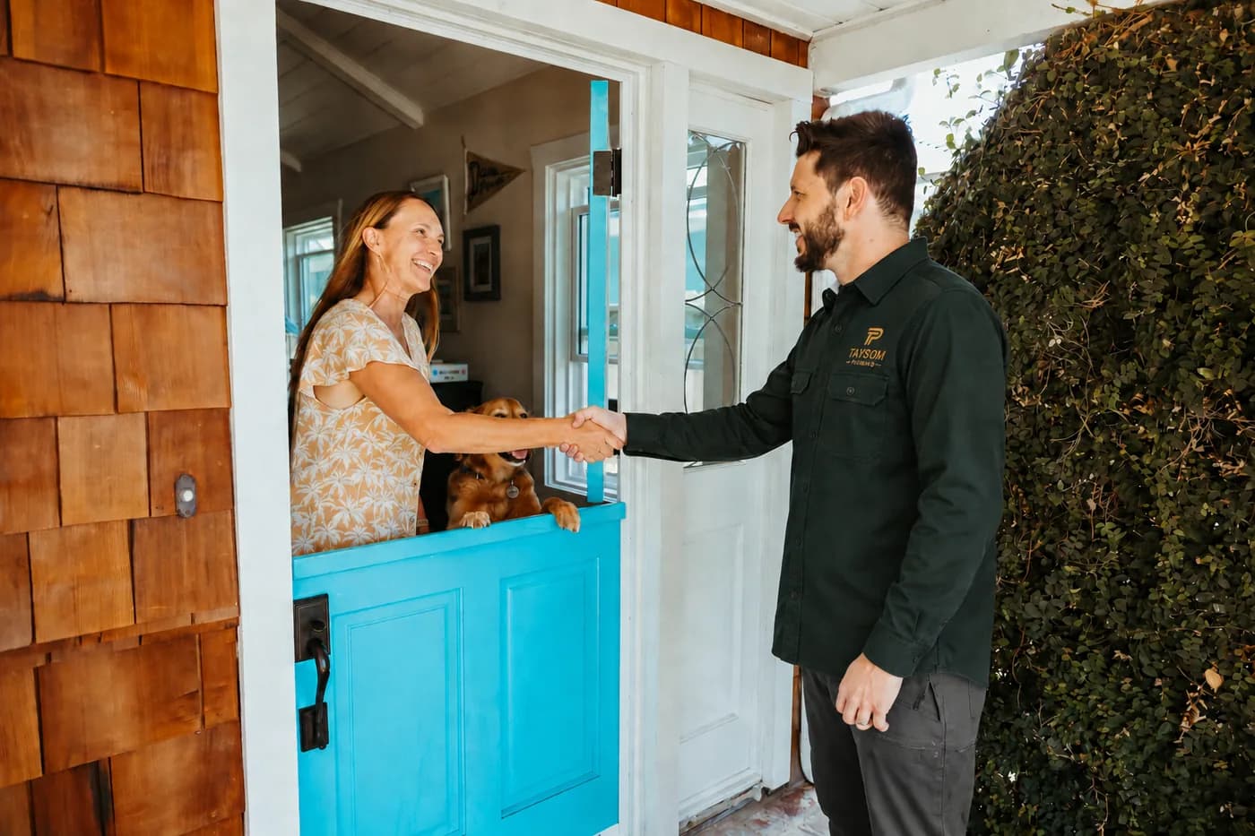 A Taysom plumber shaking hands with a homeowner at her front door