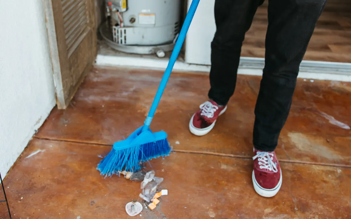Sweeping up beside a water heater cupboard after a job