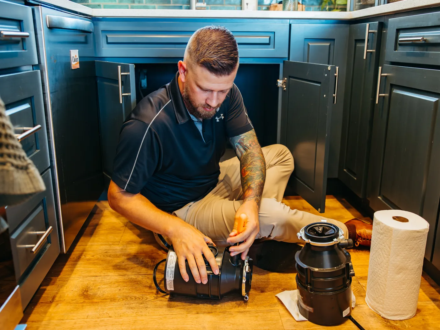 Eric Taysom fitting a garbage disposal under a kitchen sink