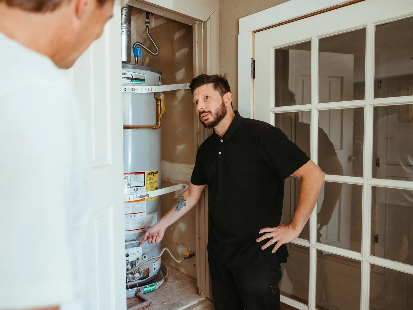 A Taysom plumber explaining a water heater to a homeowner