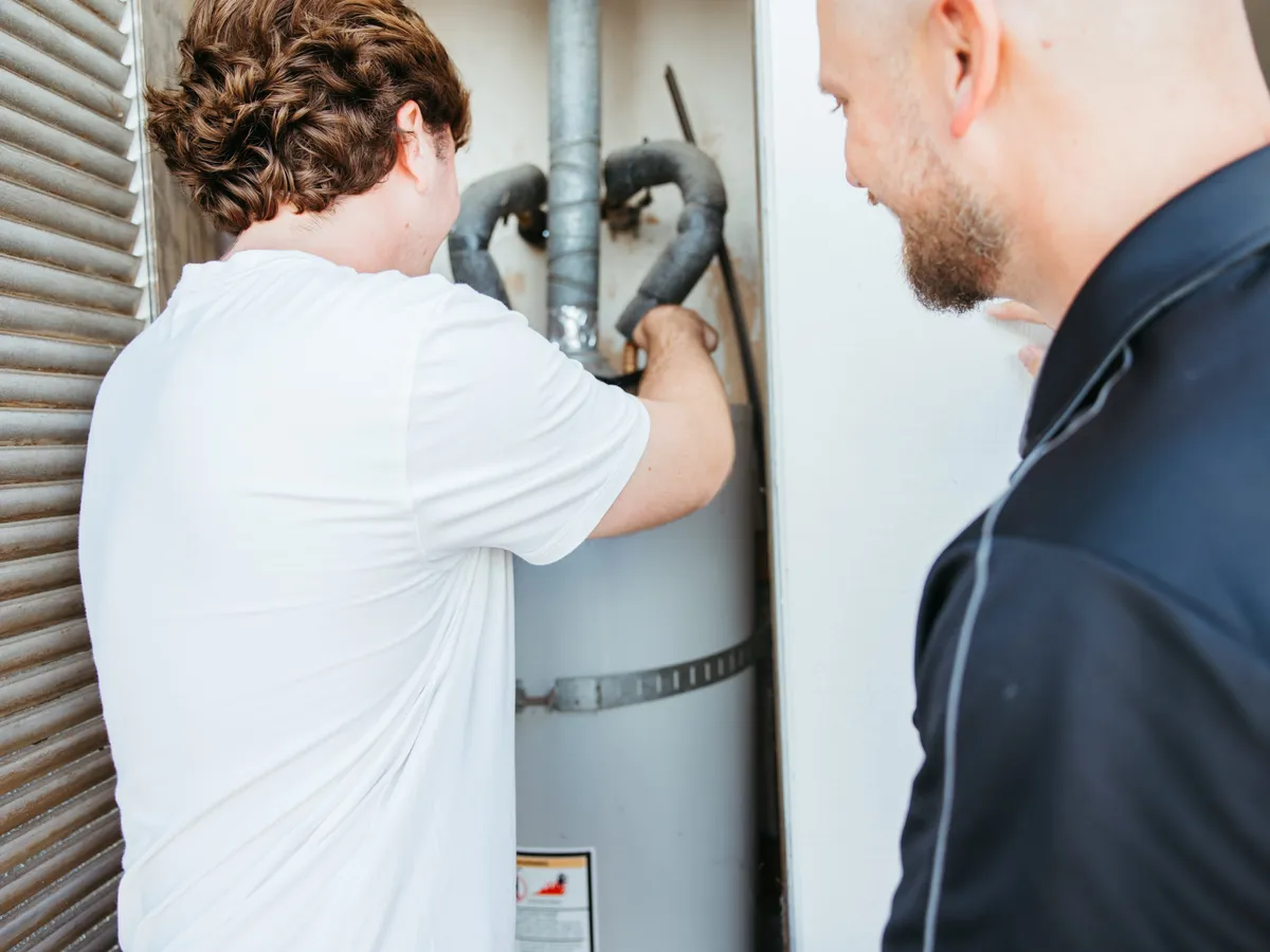 Two Taysom plumbers working on the connections at the top of a water heater
